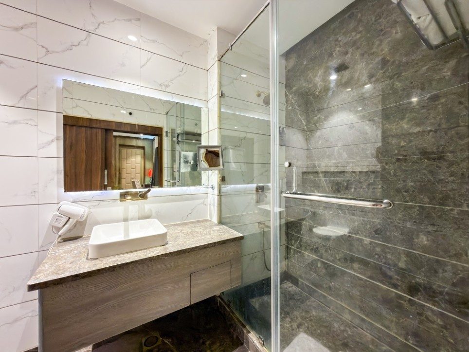 The marble bathroom of the K L Suite with glass walk-in shower, Hotel Sawera Grand